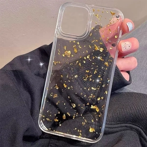Clear iPhone case with gold foil flakes shown in hand against a dark background