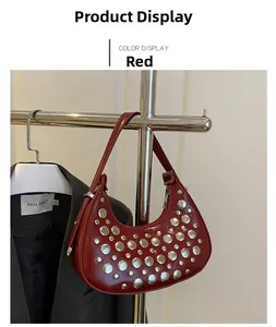 Detail of red crescent shoulder bag featuring silver rivets and glossy patent finish