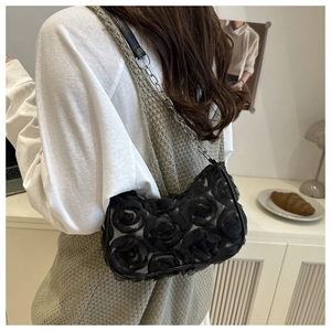 Detail view of 3D lace rose petals and silver chain strap on black shoulder bag