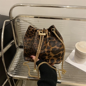 Fashionable leopard print bucket bag with gold chain and white pearl charms on display