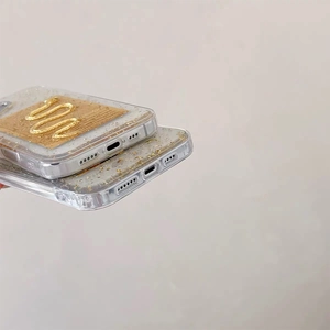 Close-up of clear phone case with embedded gold foil and elegant gold embossed patterns