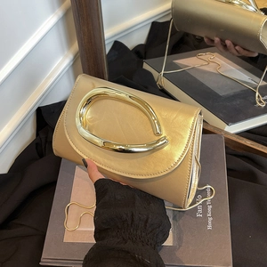 Chic gold metallic textured crossbody bag with a large curved handle and chain strap