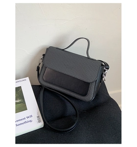Detail of grey woven texture and black leather patchwork on small crossbody bag