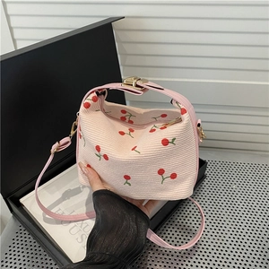 Pink woven shell bag with red cherry embroidery and matching leather handles and strap
