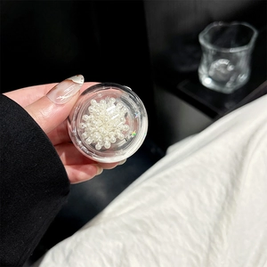 Detail of white round craft pearls for DIY phone grips inside a clear round plastic box