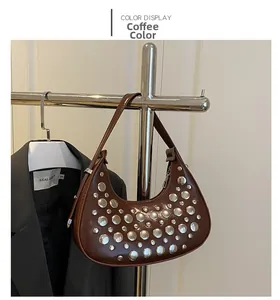 Detail of coffee brown moon bag with silver rivets hanging on metal hanger display