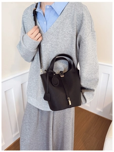 Detail of black lychee grain leather bucket bag with gold lock and leather strap