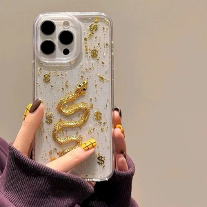 Close-up of clear iPhone case with gold foil, 3D relief snake, and dollar sign charms