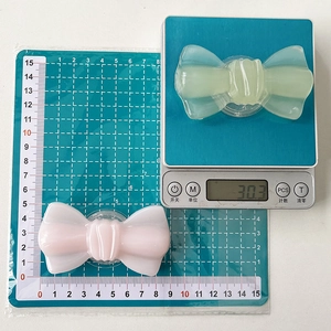 Support de téléphone en forme de nœud en résine translucide posé sur une balance