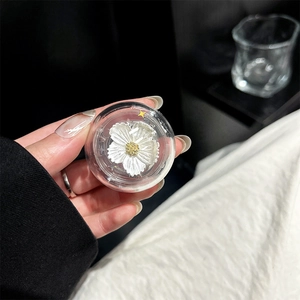 Macro shot of a clear resin phone grip featuring a white floral motif with gold accents