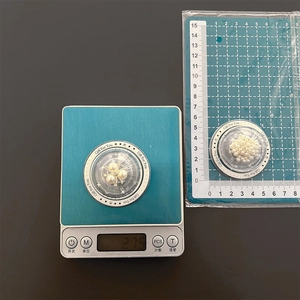 Detail view of pearl phone grip weighing 2.7g on a digital scale with measuring mat