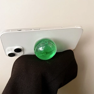 Green transparent crystal globe phone grip attached to the back of a white smartphone