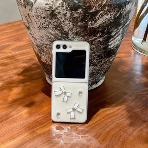Detailansicht der weißen Galaxy Z Flip Hülle mit 3D-Schleifen und Strasssteinen