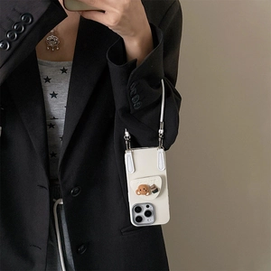 White iPhone case with 3D brown bear and coffee cup charms featuring a long lanyard strap
