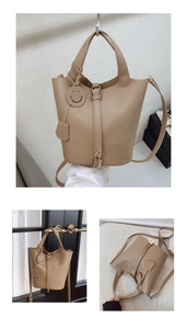Detail of beige lychee textured bucket bag with metal lock and cute smiley charm pendant