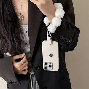 Cream iPhone Hülle mit weißem Plüsch-Pom-Pom-Armband und Kamelienblüten-Anhänger Detail.