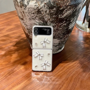 Detail der Galaxy Z Flip Hülle mit 3D-Bögen und Kristallen auf cremefarbener Fläche