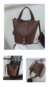 Detail of dark brown lychee texture leather bucket bag with metal padlock and smiley tag