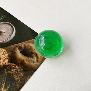 Macro detail of glossy transparent green crystal sphere phone stand with light refraction
