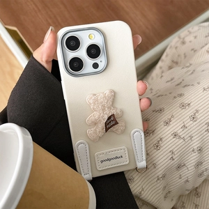 Detail of cream iPhone case with 3D plush teddy bear and leather goodluck patch