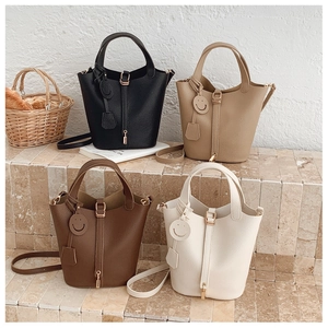 Detail of four bucket bags in black, khaki, brown, and cream with lychee grain texture