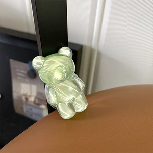 Close-up of a translucent green textured bear-shaped phone grip on a brown surface
