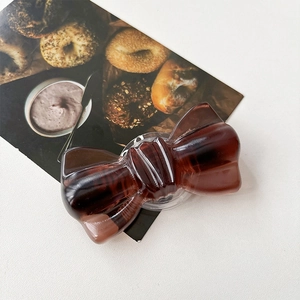 Gros plan d'un support de téléphone en forme de nœud marron foncé avec texture ambre