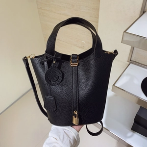 Minimalist black pebbled leather bucket bag with lock closure and top handle strap