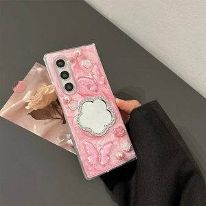 Dettaglio macro della cover rosa con specchio a fiore in strass e farfalle