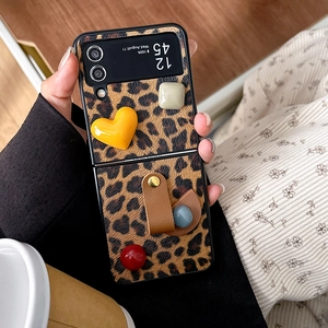Dettaglio custodia Galaxy Z Flip con stampa leopardata, cuore 3D e cinturino a perle