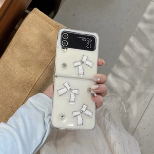 Detailansicht der Galaxy Z Flip Hülle mit weißen 3D-Schleifen und Diamant-Akzenten