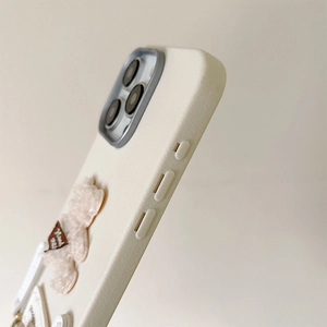 Close-up of creamy white iPhone case featuring a 3D plush bear and soft matte leather texture
