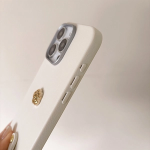 Nahaufnahme weiße iPhone-Hülle mit goldener Kamelie und erhöhtem Kameraschutz