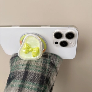 Detail of a pastel green magnetic phone grip featuring a yellow bow and Good Luck text