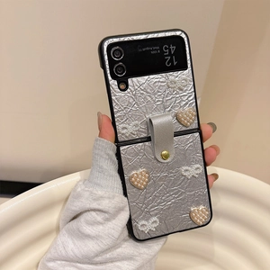 Détail de la coque en cuir argenté pour Samsung Z Flip avec cœur en perles et un nœud