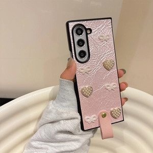 Vue détaillée de la coque en cuir plissé rose avec nœud perlé et breloque cœur