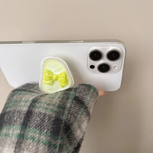 Detail of light green translucent bow phone grip attached to a white smartphone back