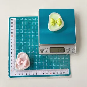 Macro shot showing dimensions and weight of iridescent bow phone stands in pink and green