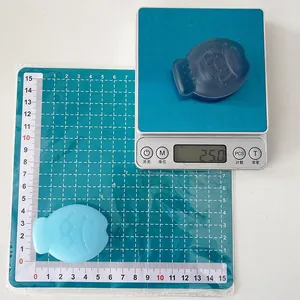 Detail view of fish-shaped phone grip on a scale showing 5.5cm length and 25g weight