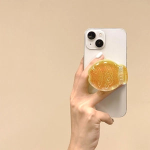 Detail of amber glitter resin phone grip showing 3D texture on white smartphone case