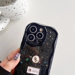 Detail of glitter black iPhone case with metal rose and smile tag in lifestyle setting