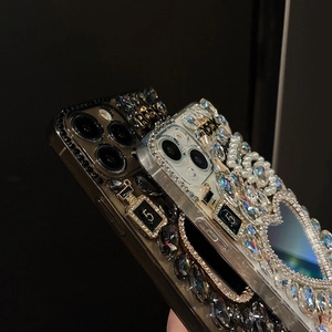 Detail of luxury iPhone case with rhinestones, pearls, and a metal perfume bottle charm