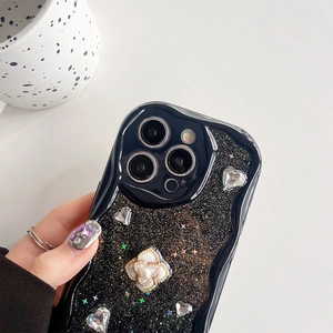 Détail de coque pailletée noire avec cœurs 3D et fleur en perle sur bord ondulé