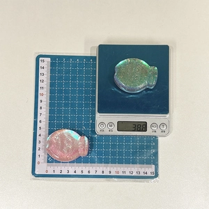 Detailed view of fish-shaped phone grip showing 38.8g weight on electronic scale