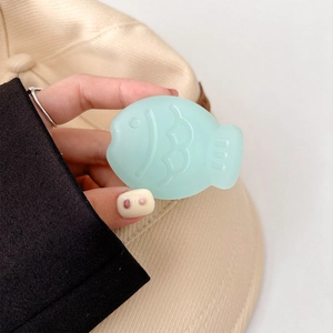 Close-up of mint green fish-shaped phone grip with matte finish held by hand