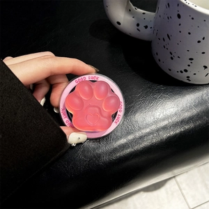 Close-up of pink translucent cat paw phone grip with Good Luck text on black background