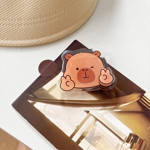 Close-up of cute cartoon capybara acrylic badge on brown card with a rustic aesthetic