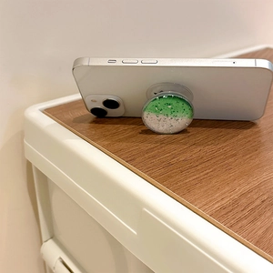 Detail of green and silver glitter phone socket grip on a white smartphone