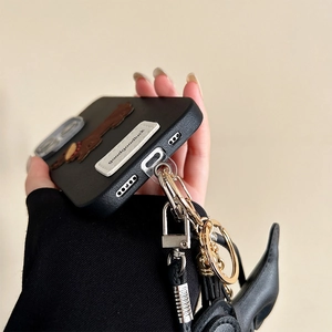 Detail of black faux leather phone case with strap attachment and goodluck embroidery tag