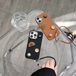 Detail of leather phone cases with geometric buttons and hand strap for iPhone